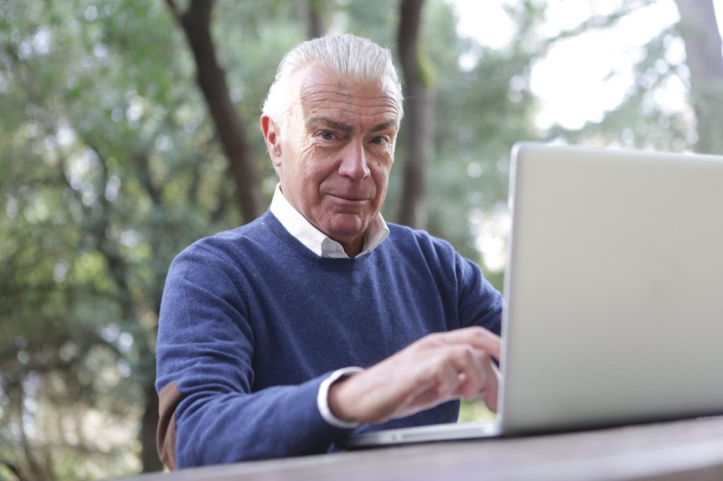 man in blue sweater typing on computer laptop